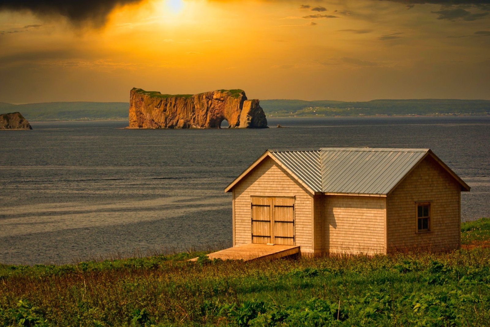 Le Rocher Percé au coucher du soleil, avec un cabanon de pêcheur sur la falaise